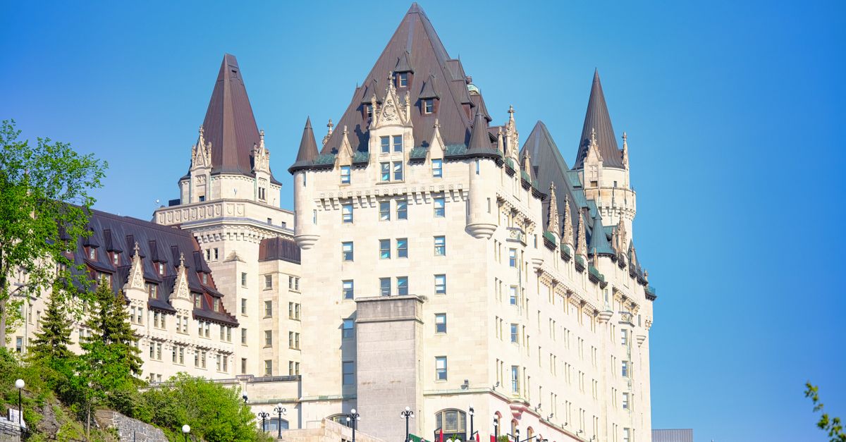 Sunlit view of the iconic Fairmont Château Laurier in Ottawa, Canada, against a clear blue sky.